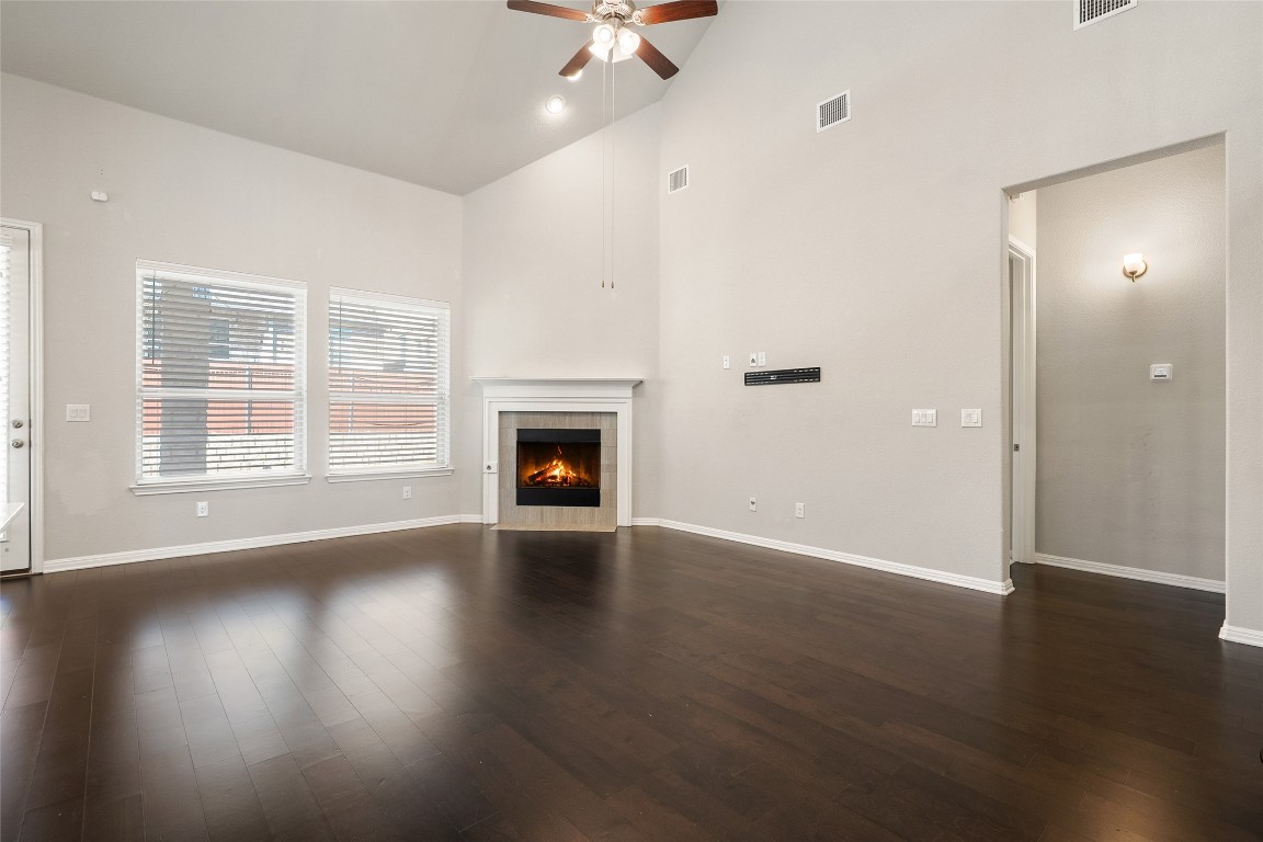 2909 Zelma Drive Cedar Park, TX 78613 - Photo 6 of 40 Unfurnished living room featuring a tile fireplace, a ceiling fan, high vaulted ceiling, and dark wood-style floors