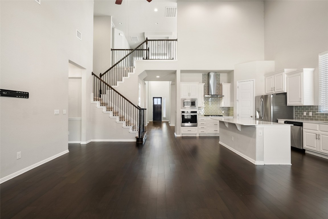 2909 Zelma Drive Cedar Park, TX 78613 - Photo 8 of 40 Kitchen featuring white cabinetry, wall chimney exhaust hood, a kitchen island, a kitchen breakfast bar, and stainless steel appliances