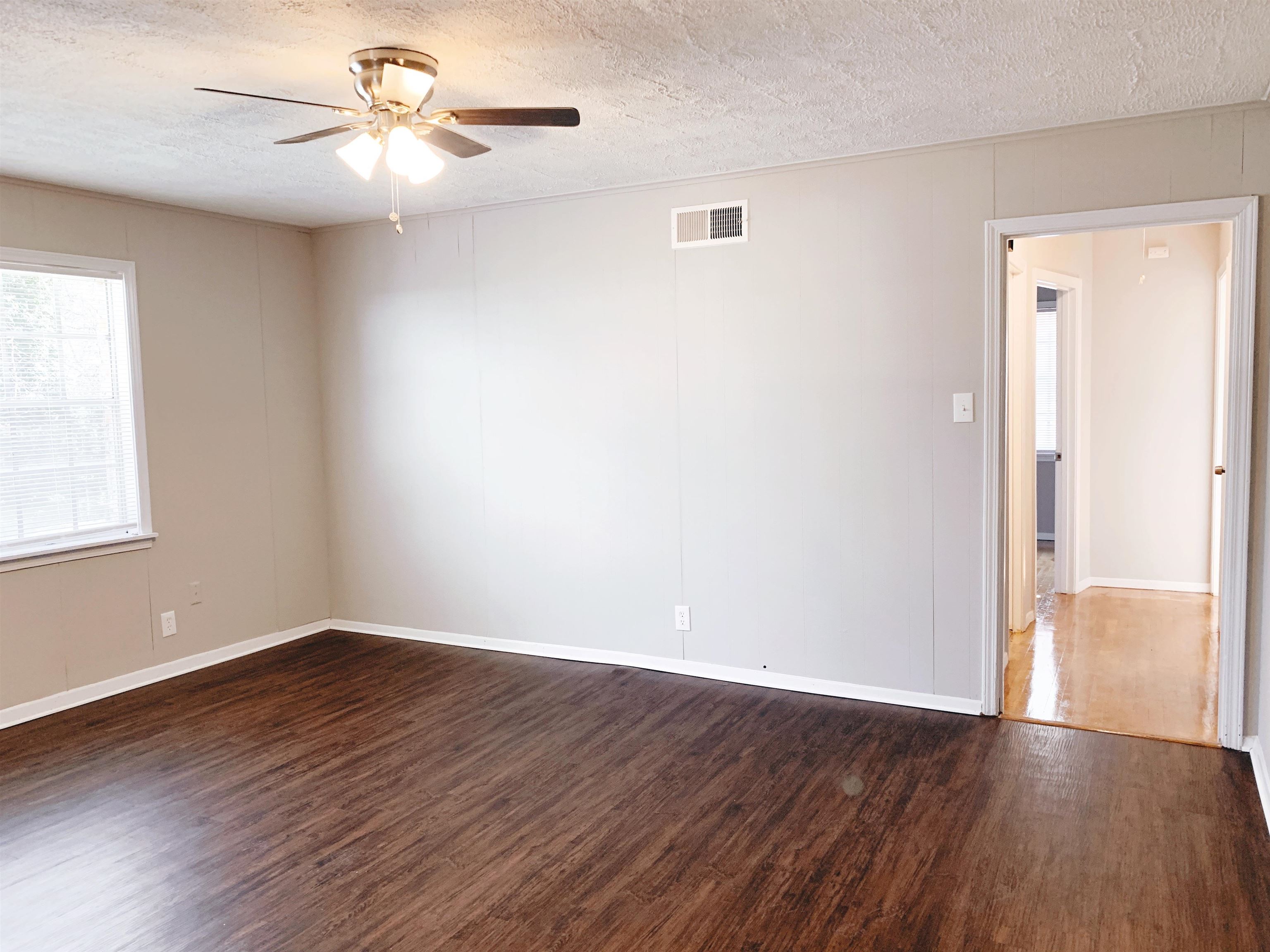 1084 Rutland Road Memphis, TN 38114 - Photo 8 of 13 an empty room with wooden floor chandelier fan and windows