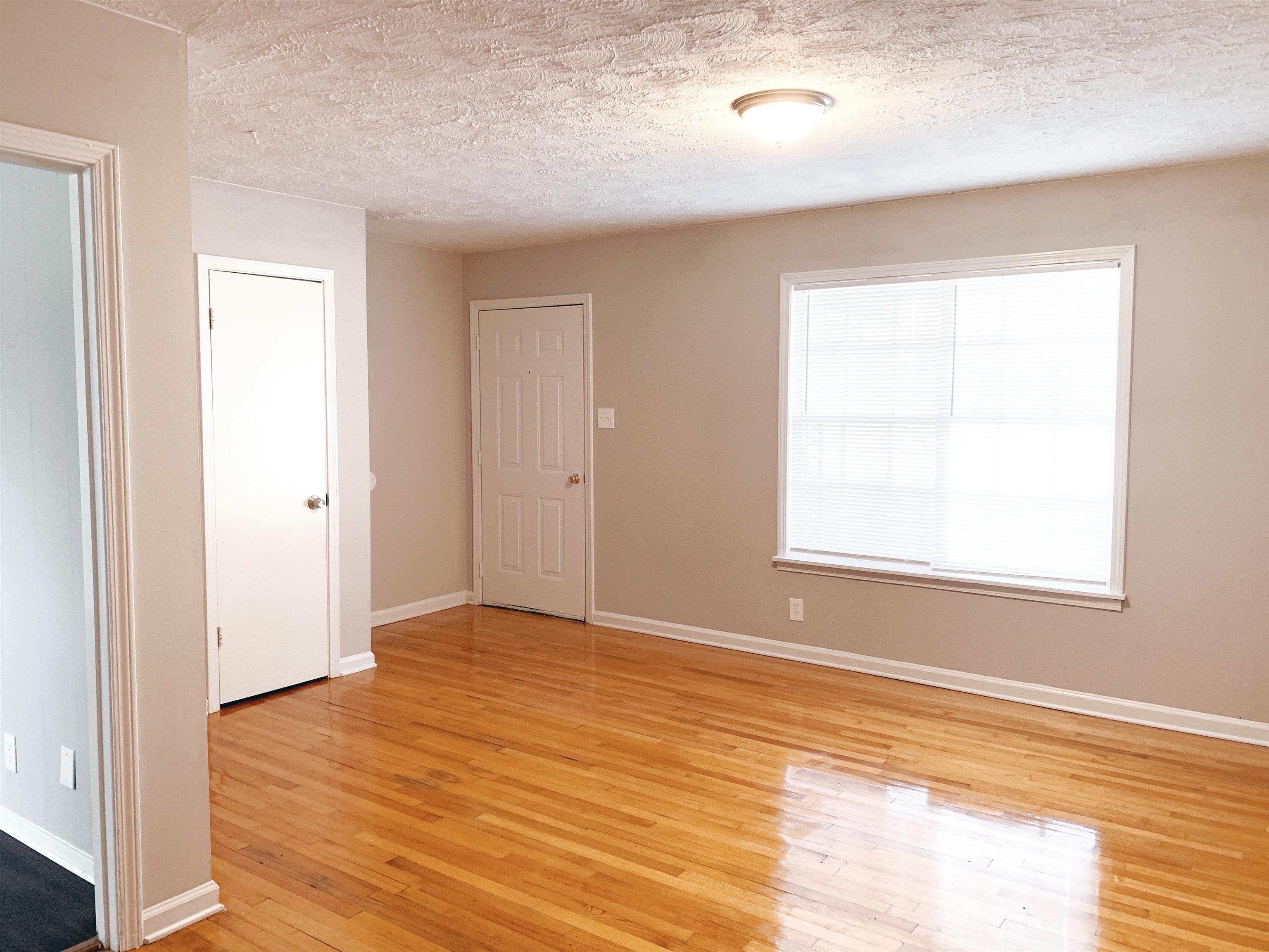1084 Rutland Road Memphis, TN 38114 - Photo 9 of 13 a view of an empty room with wooden floor and a window