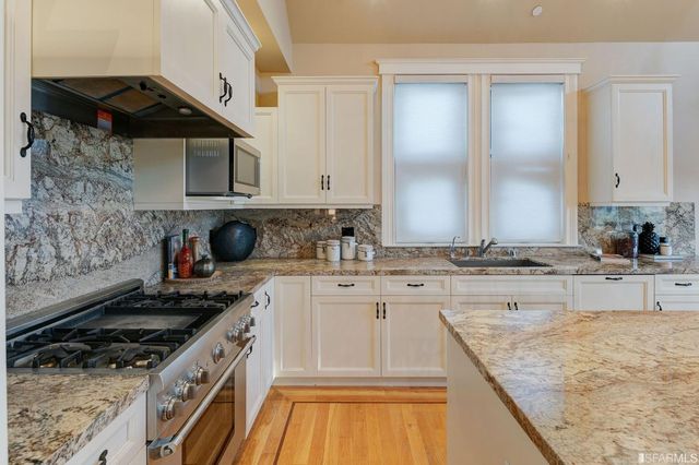a kitchen with stainless steel appliances granite countertop a sink a stove counter space and cabinets