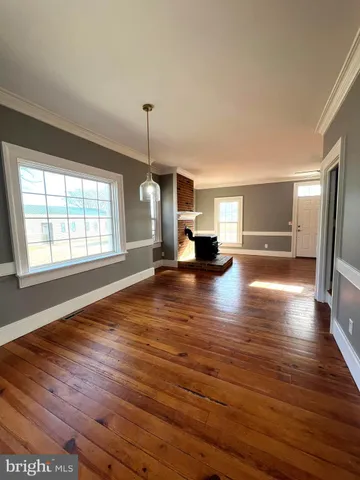 a view of empty room with wooden floor and window