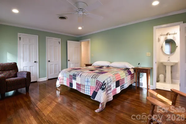 a bedroom with a bed a mirror on dresser and a wooden floor