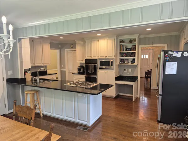 a kitchen with stainless steel appliances kitchen island granite countertop a stove and cabinets
