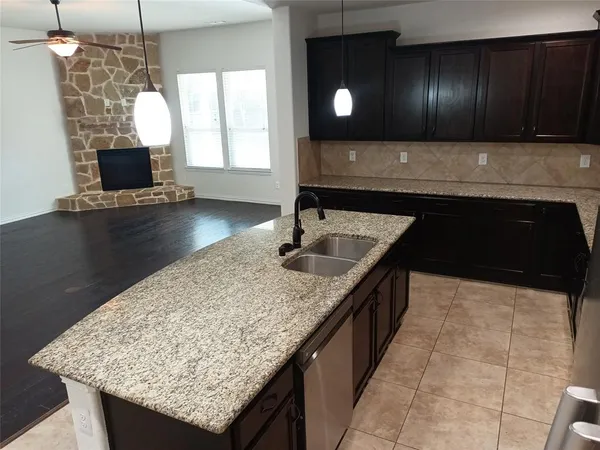 a kitchen with kitchen island granite countertop a sink a counter top space and cabinets
