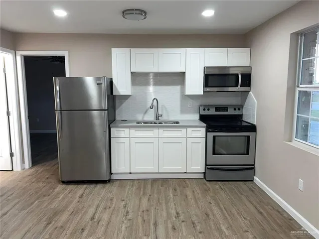 a kitchen with a refrigerator stove and white cabinets