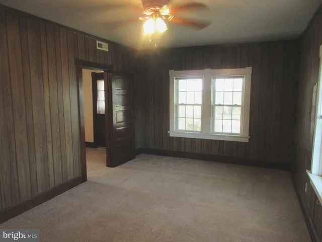 an empty room with windows and chandelier fan