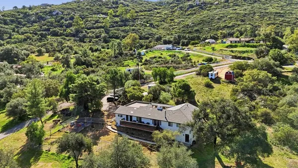 an aerial view of residential house with outdoor space and trees all around