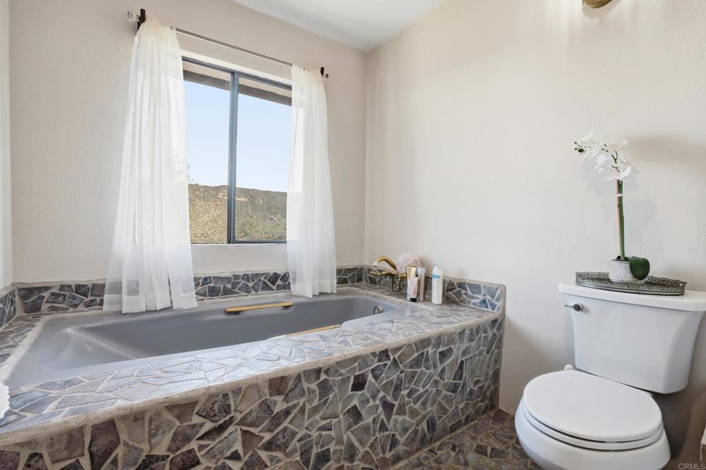 3340 Skytrail Ranch Road Jamul, CA 91935 - Photo 31 of 42 a bathroom with a granite countertop sink a toilet and mirror