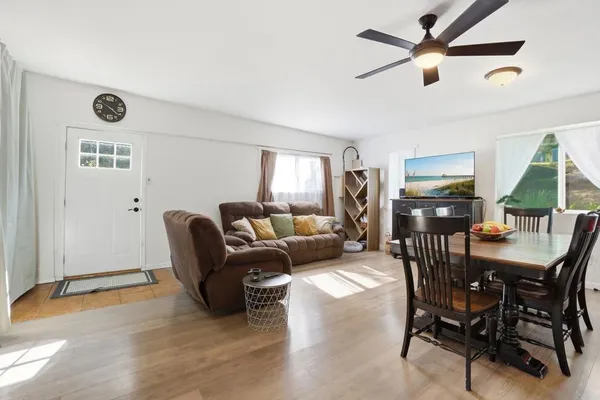 a view of a livingroom and a dining room with furniture wooden floor and a chandelier