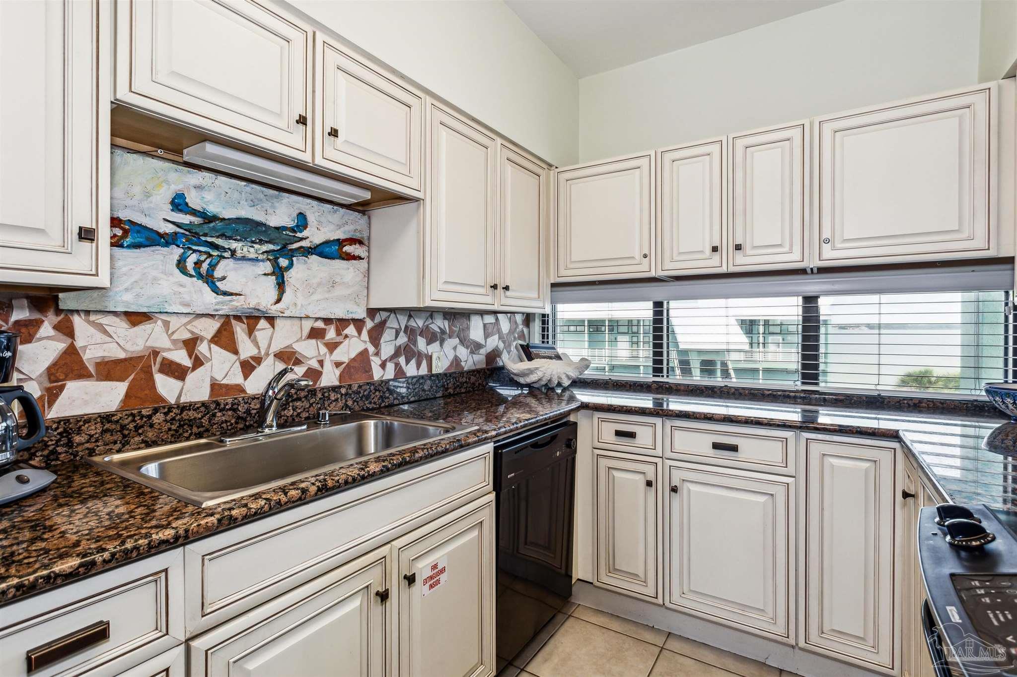 1390 Fort Pickens Road, Unit 229 Pensacola Beach, FL 32561 - Photo 16 of 47 a kitchen with granite countertop white cabinets and white appliances