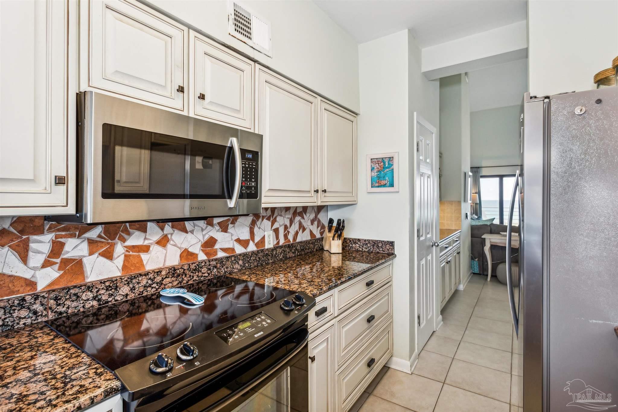 1390 Fort Pickens Road, Unit 229 Pensacola Beach, FL 32561 - Photo 18 of 47 a kitchen with granite countertop a stove and a microwave
