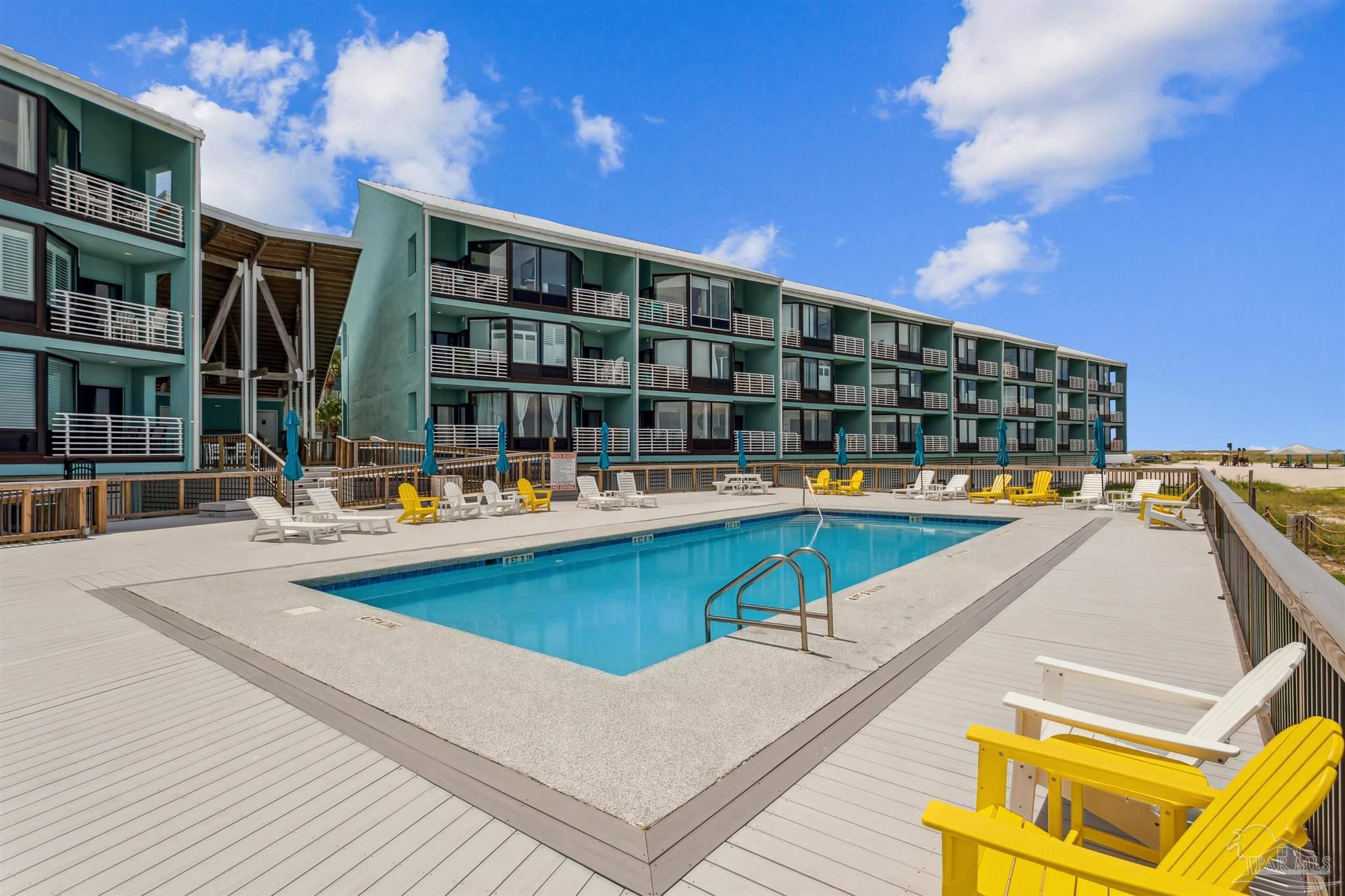 1390 Fort Pickens Road, Unit 229 Pensacola Beach, FL 32561 - Photo 33 of 47 a view of swimming pool with outdoor seating and buildings in the background