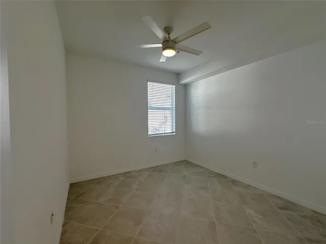 an empty room with a ceiling fan and window