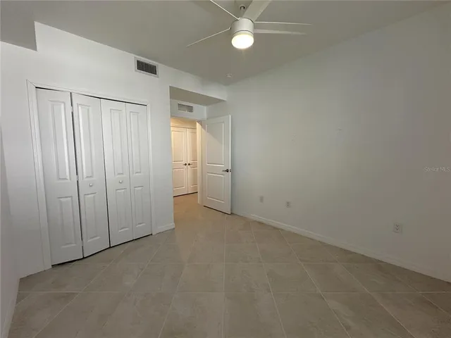 an empty room with a ceiling fan and closet area