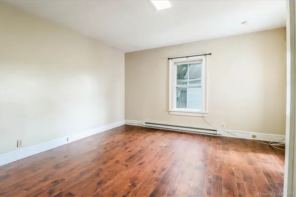 a view of an empty room with wooden floor and a window
