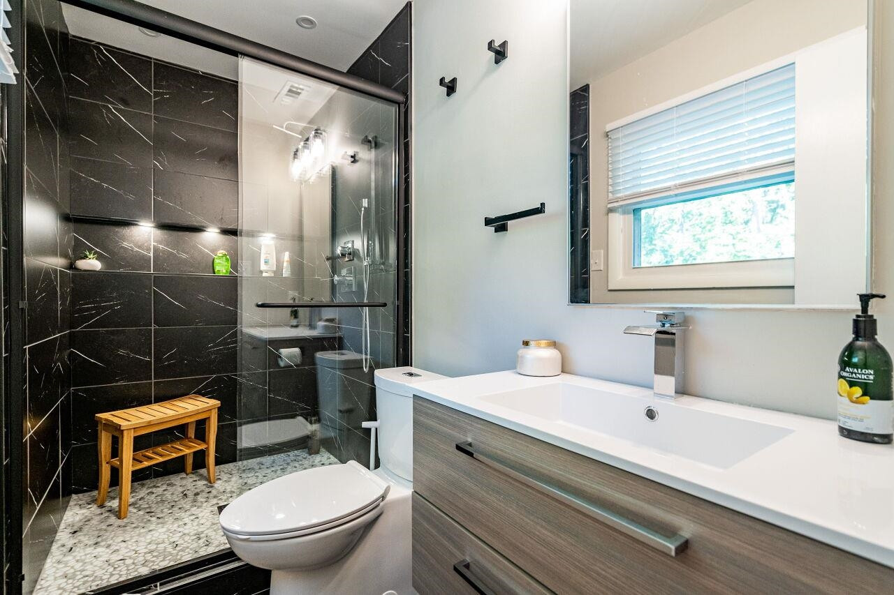 1500 Windbur Place Raleigh, NC 27609 - Photo 13 of 30 Completely remodeled in '21 with Floating (single) Vanity, Extra-Large Medicine Chest. Shower features Rainhead and Wand, Pebble-Stone shower floor, custom Lighted Niche. Also an all-important window! Owner's Suite Bath