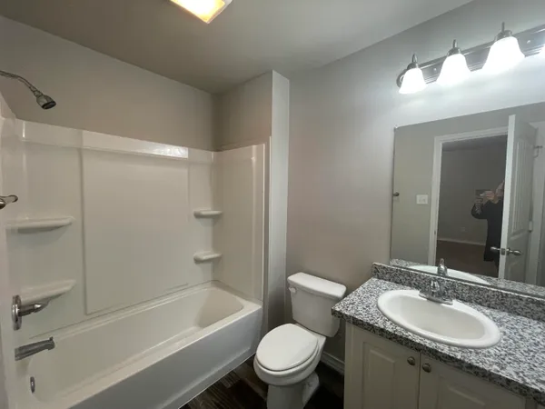 a bathroom with a granite countertop toilet a sink and a mirror