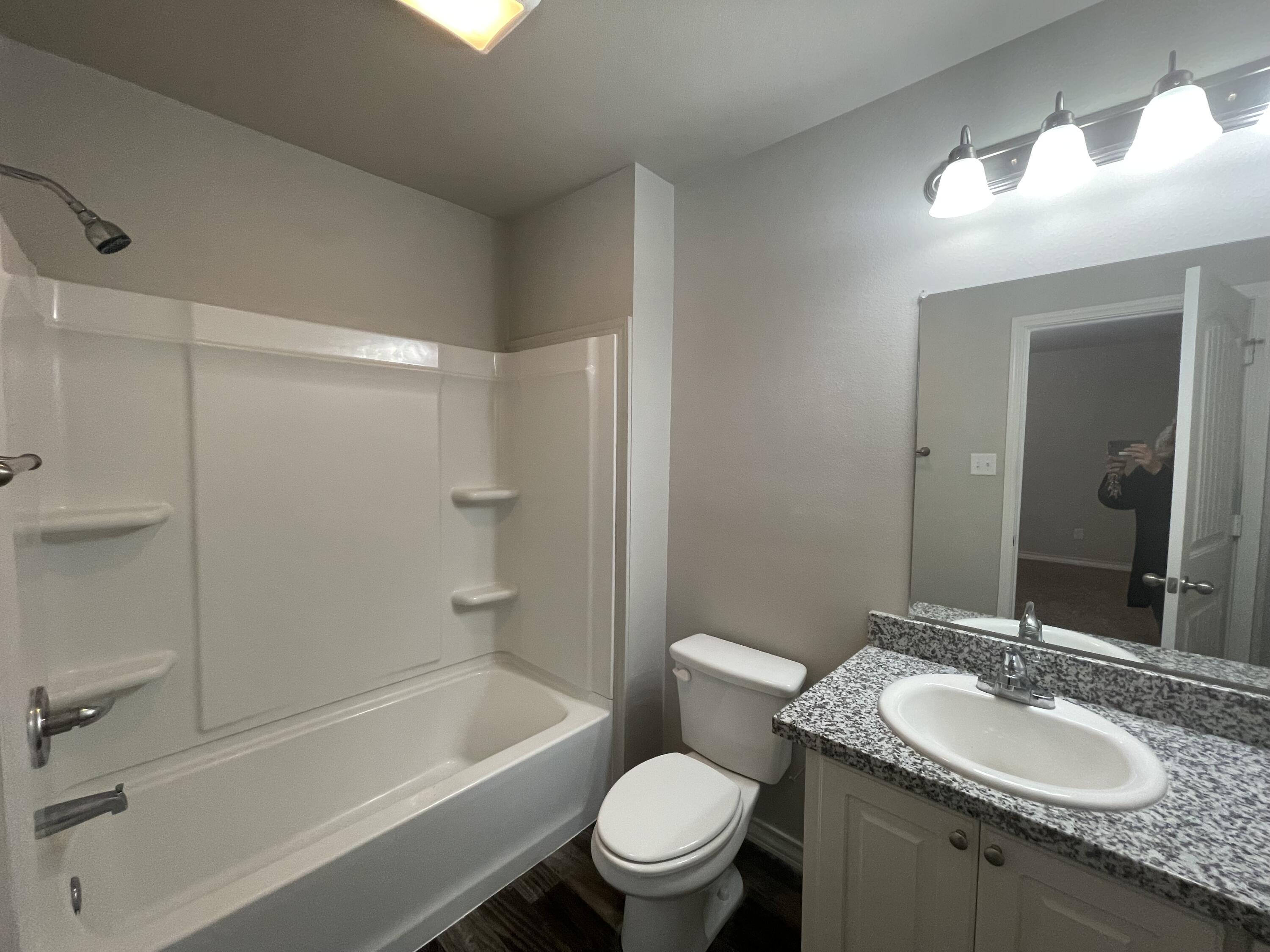 6040 24th Street, Unit 29 Lubbock, TX 79407 - Photo 11 of 15 a bathroom with a granite countertop toilet a sink and a mirror