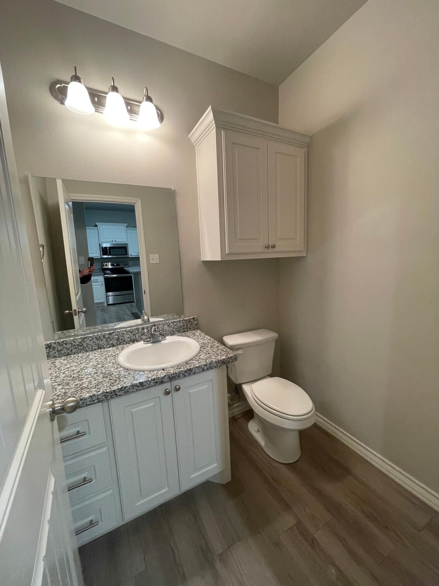 6040 24th Street, Unit 29 Lubbock, TX 79407 - Photo 15 of 15 a bathroom with a granite countertop sink a toilet and a mirror