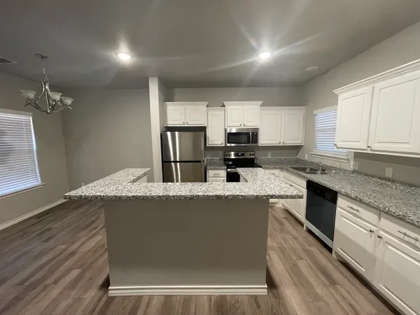 a kitchen with kitchen island granite countertop a stove a sink and a refrigerator