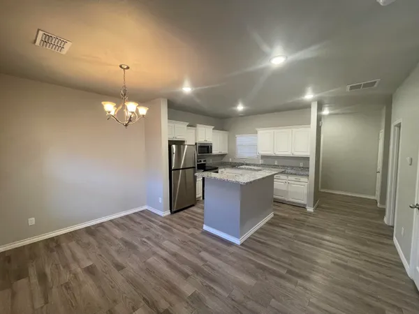 a view of kitchen with granite countertop cabinets and refrigerator
