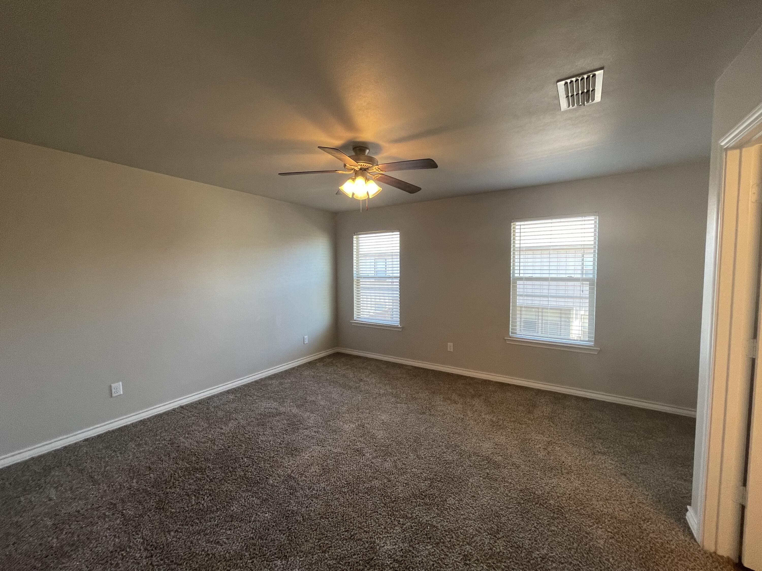 6040 24th Street, Unit 29 Lubbock, TX 79407 - Photo 6 of 15 an empty room with windows and chandelier fan