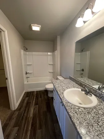 a bathroom with a granite countertop sink a mirror and a bathtub