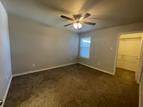an empty room with a chandelier fan and windows