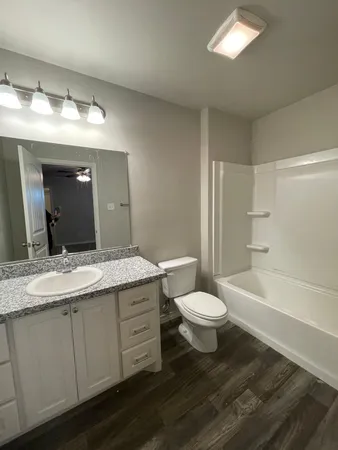 a bathroom with a granite countertop sink toilet a large mirror and a tub