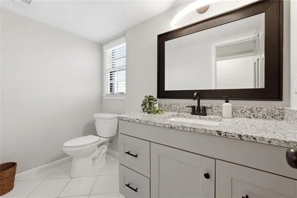 a bathroom with a granite countertop toilet sink and mirror