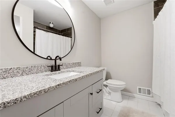 a bathroom with a granite countertop toilet sink and mirror