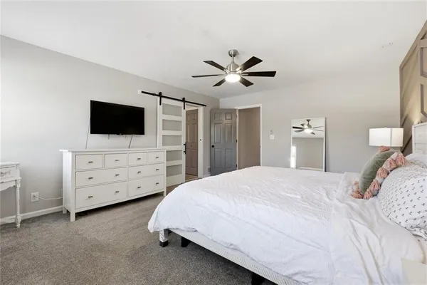 a bedroom with a bed a dresser and flat screen tv