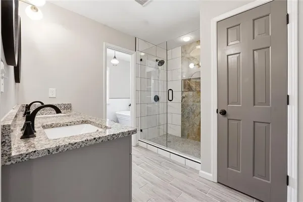 a bathroom with a granite countertop sink mirror and shower