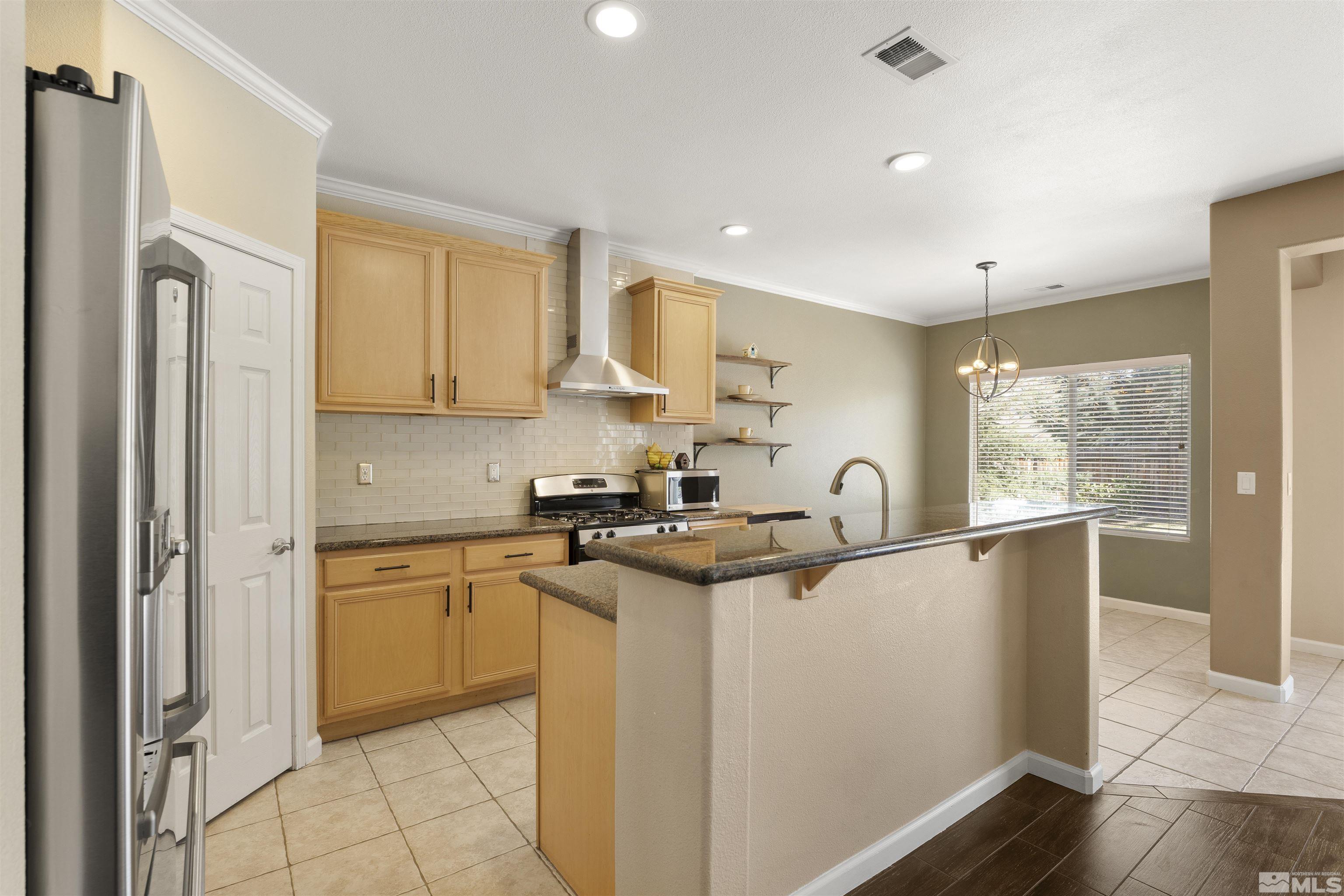 10200 Wolf Ridge Way Reno, NV 89521 - Photo 9 of 40 a kitchen with stainless steel appliances granite countertop a refrigerator a sink a stove and white cabinets with wooden floor