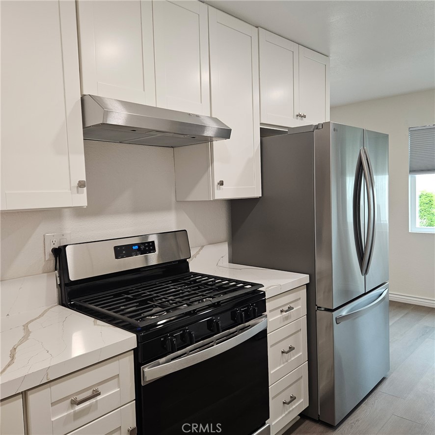 1051 Springfield Street, Unit C Upland, CA 91786 - Photo 4 of 14 a kitchen with stainless steel appliances white cabinets and a stove top oven