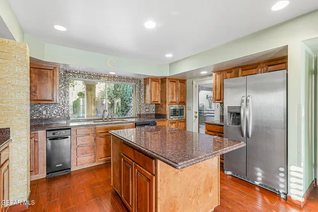 a kitchen with stainless steel appliances granite countertop a refrigerator a stove and a wooden floors