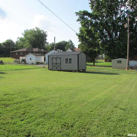 a view of a big house with a big yard and large trees