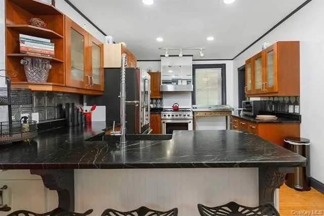 a kitchen with stainless steel appliances granite countertop a refrigerator a stove and a sink with wooden floor