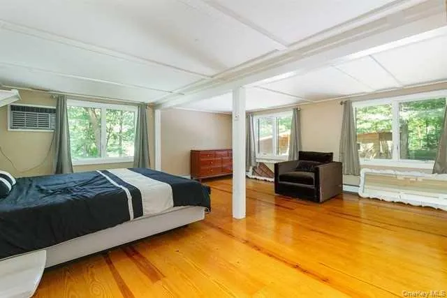 a spacious bedroom with a bed and wooden floor