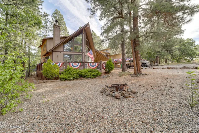 a view of a blue house with a yard and large trees
