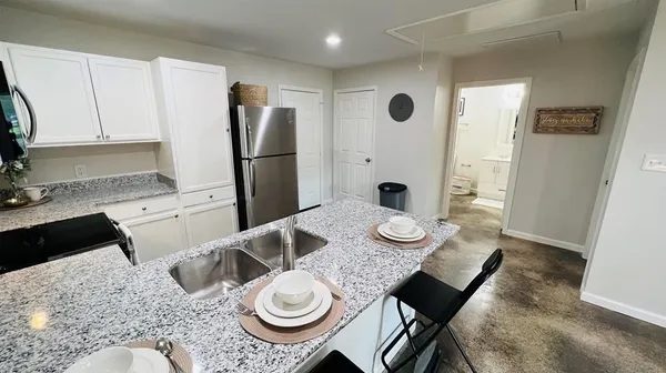 a kitchen with sink refrigerator dining table and chairs