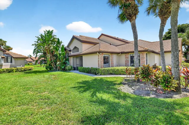 a front view of a house with a garden and trees
