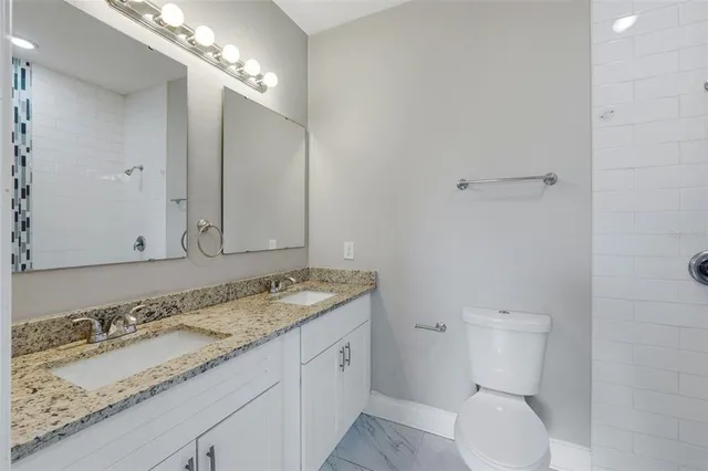 a bathroom with a granite countertop double vanity sink and mirror
