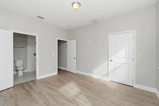 a view of an empty room with wooden floor and a bathroom