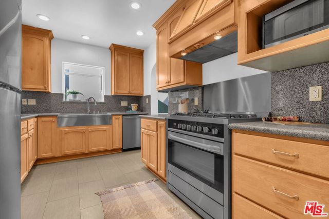 a kitchen with stainless steel appliances granite countertop a stove a sink and a microwave