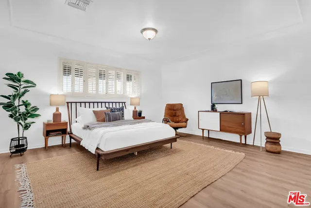 a bedroom with a bed and a potted plant on dresser