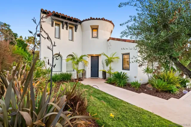 a view of a house with a yard and a large tree