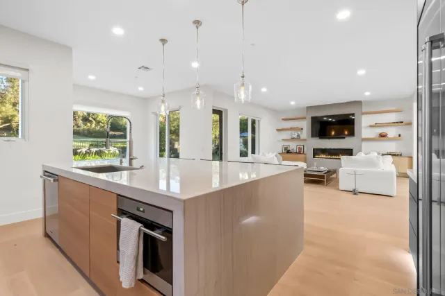 a large kitchen with stainless steel appliances kitchen island a large counter top a stove a chimney a sink and a refrigerator