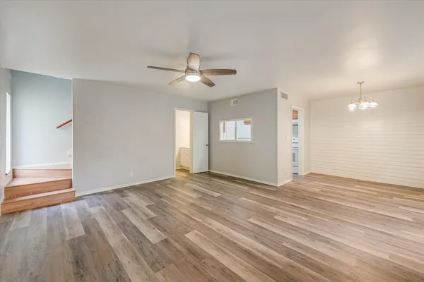an empty room with wooden floor fan and windows